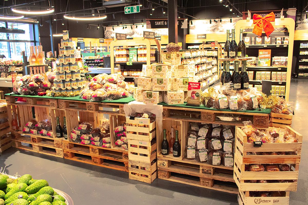 L'image montre un étalage de produits alimentaires, éclairés par plusieurs luminaires. Les produits sont présentés sur des palettes en bois.