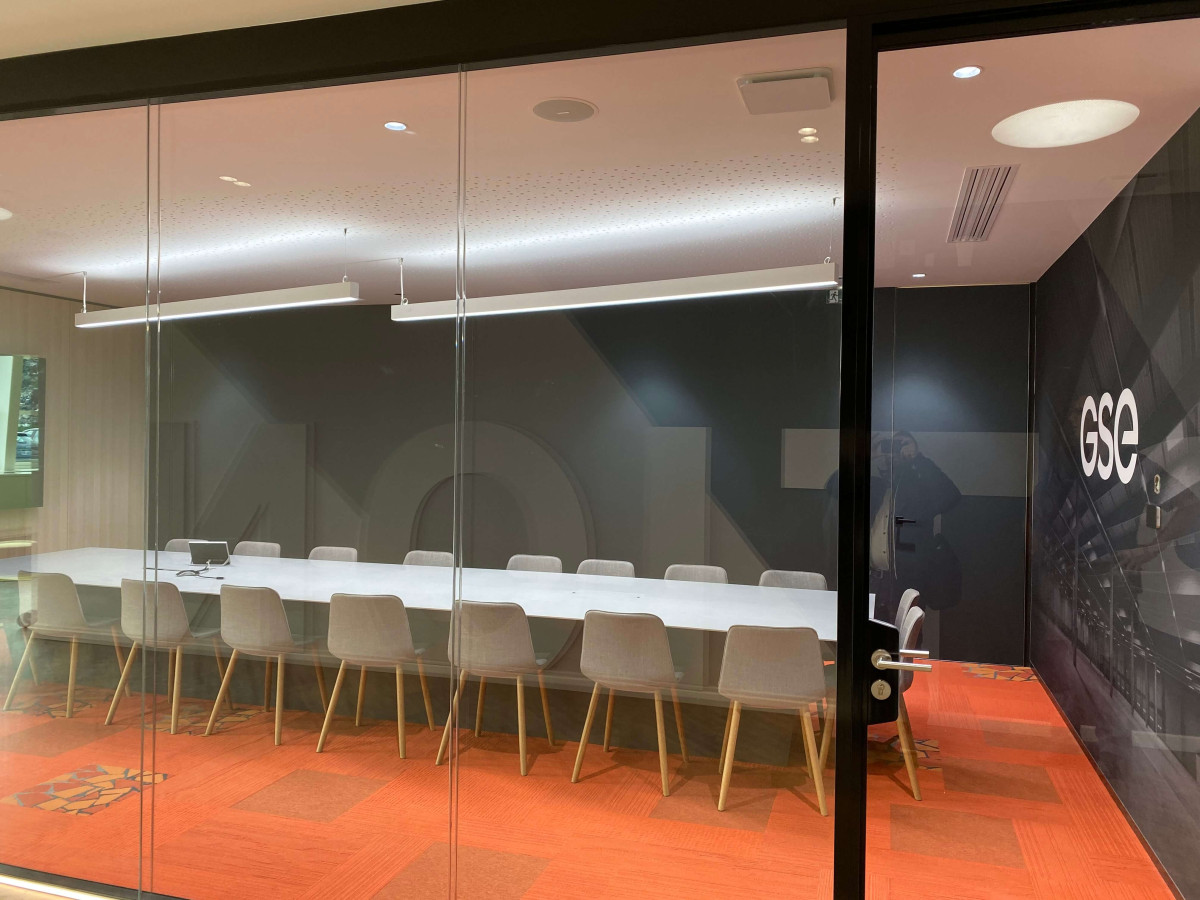 Salle de réunion très spacieuse, équipée de grands luminaires suspendu au plafond.