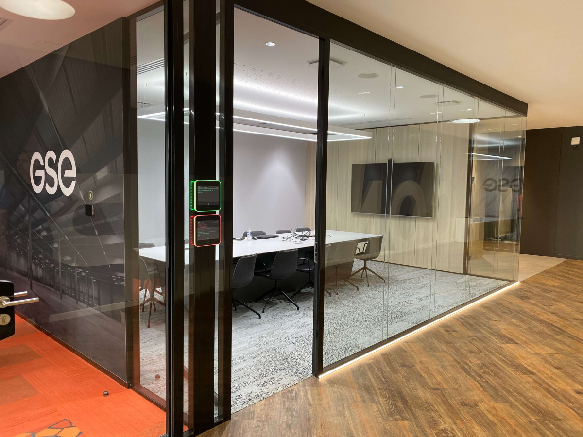 Salle de réunion très spacieuse, équipée d’un grand luminaire rectangulaire suspendu au plafond.