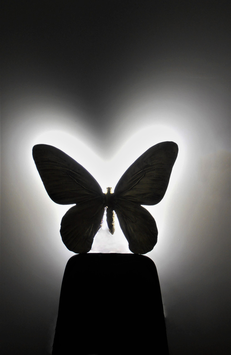 Une applique murale en forme de papillon. La lumière est placée derrière le papillon. Design minimaliste et moderne.