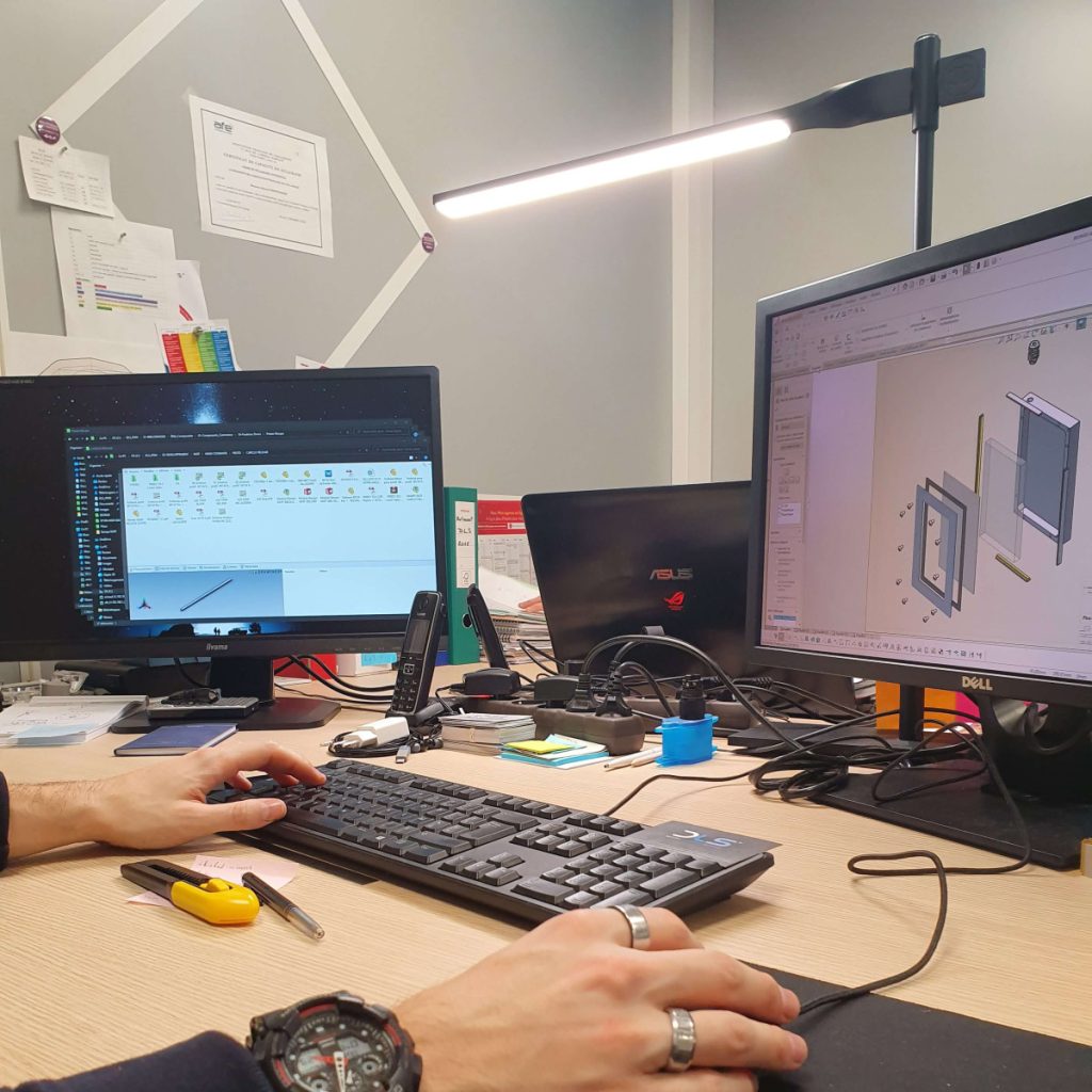 Ingénieur travaillant sur un ordinateur de bureau avec double écran, concevant un modèle 3D en dans un bureau technique.
